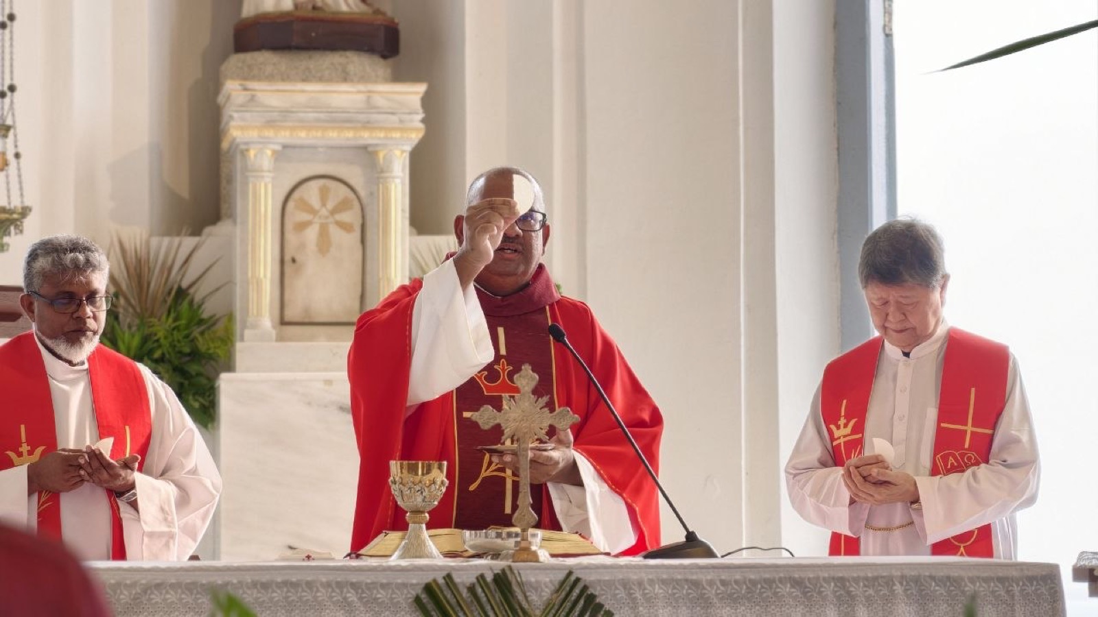 Priests in red vestments at the altar during a liturgy